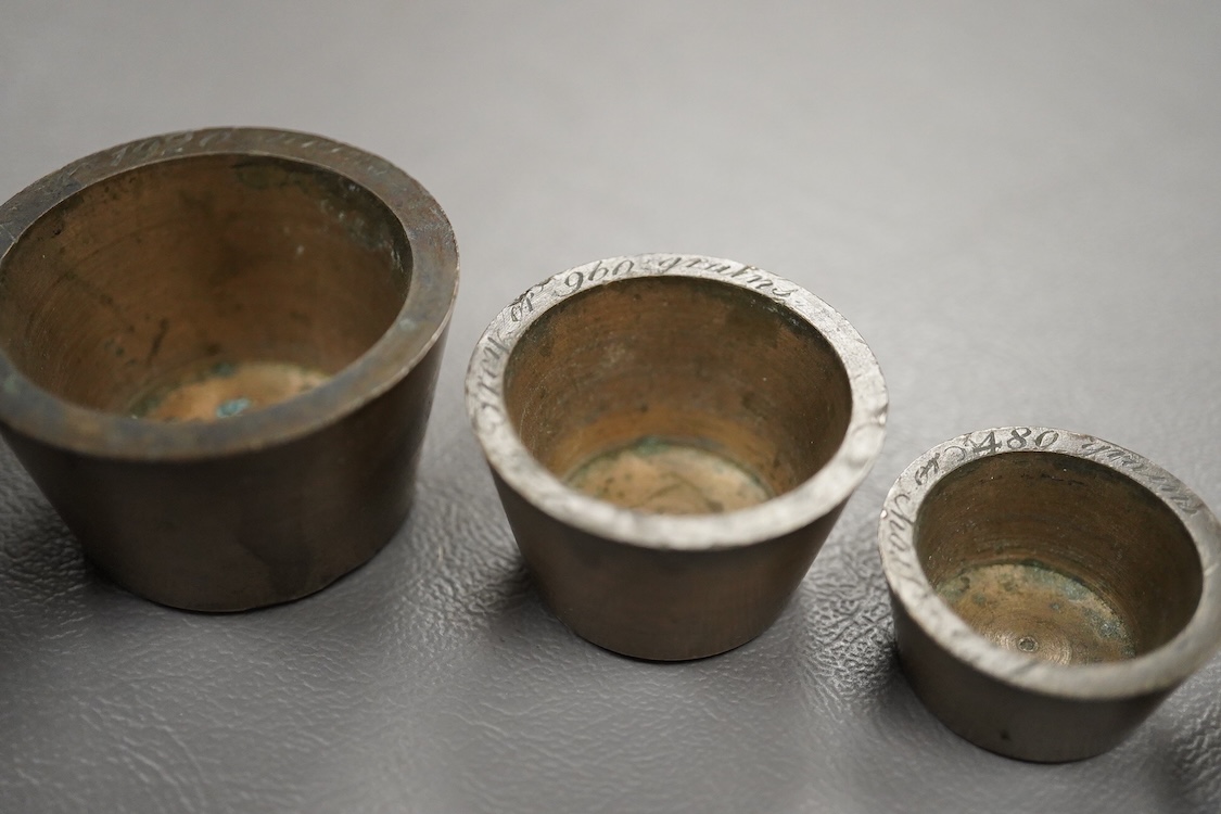 Two sets of bronze Troy nesting weights, one incomplete, with engraved rims, largest 8oz